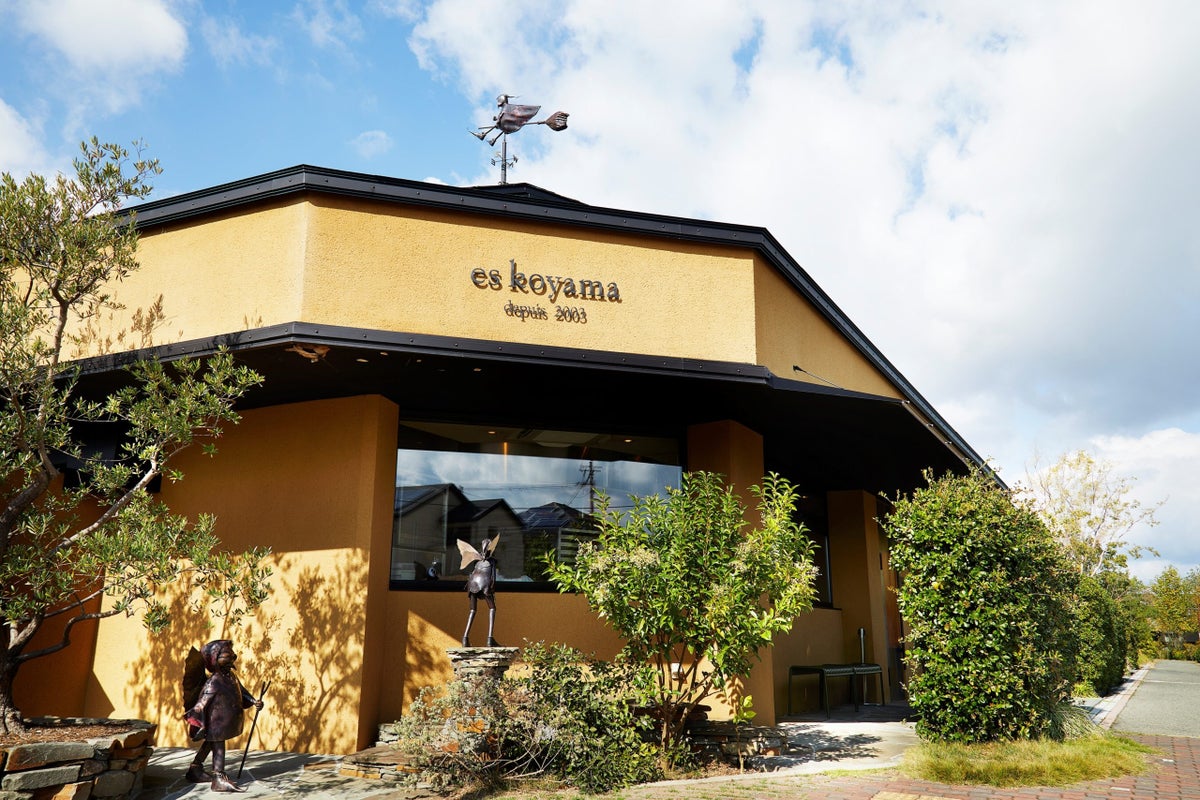 PATISSIER eS KOYAMA 2003年、兵庫県三田市に開業。1,500坪の敷地にはパン、チョコレートなどの専門店の他、お菓子教室やギフトサロンも併設。敷地内をただようお菓子の香りや、四季折々で表情を変えるお庭の草花、点在するユニークな姿の銅人形など、五感で楽しめる空間を展開。「The Sweet Trick（お菓子でいたずら）」をコンセプトに、驚きと喜びをお菓子に吹き込み、小さいお子様からお年を召された方まで幅広い世代のお客様に美味しさと楽しさを届けている。