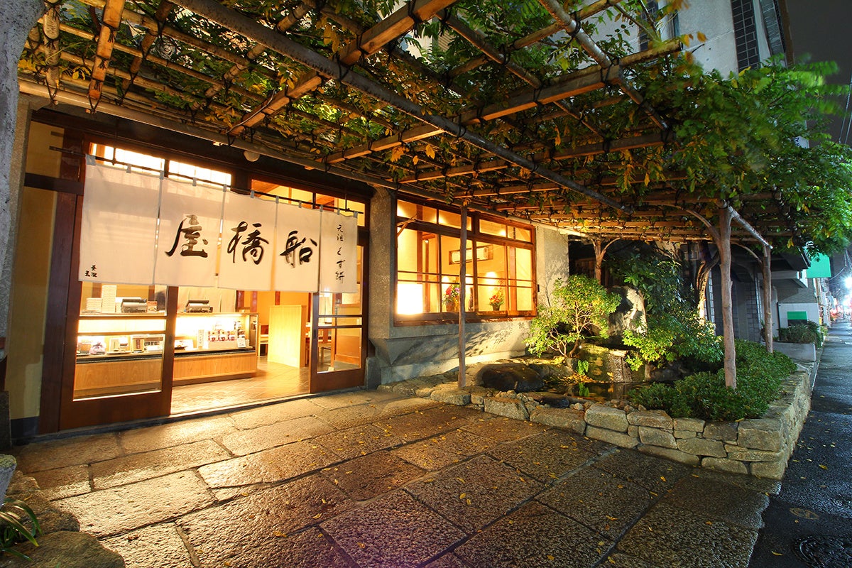 船橋屋について 1805年江戸時代に創業し、2026年で創業221年目を迎えた関東風のくず餅屋です。 船橋屋のくず餅は、「小麦澱粉」を450日乳酸菌発酵させて蒸し上げる【和菓子では珍しい発酵食品】。長期間乳酸菌発酵させているからこそ、独特の歯ごたえと弾力が生み出されます。 また、自然のものをそのままお客様にお届けしたいという想いから、保存料を使わない自然な製法にこだわり続けています。 発酵食品であり、保存料無添加である伝統和菓子が今、健康を意識する人々から注目されております。