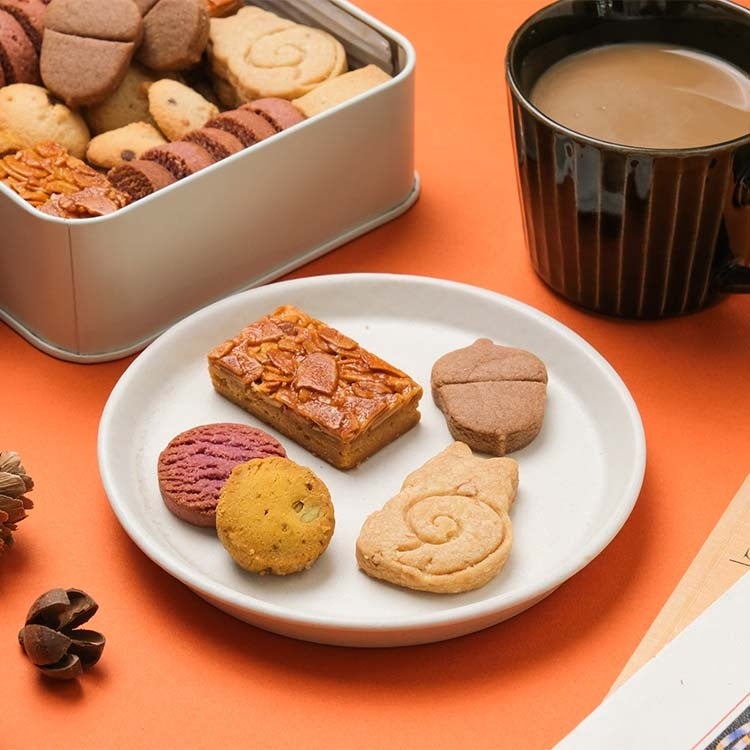 「秋のクッキー缶を作るなら、と考えた時に、まず思い浮かんだのがりすとどんぐり。缶を開けると、ほっこり愛らしいふたつのクッキーが目を引くクッキー缶ができました。ナッツやかぼちゃ、紫芋を使ったクッキーを中心に、おなじみのチョコチップクッキーやバニラ風味のショートブレッドを組み合わせています。さくほろのクッキー、ザクッとしたショートブレッド、カリッとしたフロランタンと食感も豊富です。のんびり秋のおやつタイムをお届けできたら嬉しいです。」
